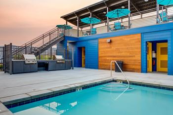 the pool and poolside deck of a blue building with a swimming pool and stairs